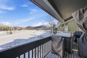 Snow covered back of property with a mountain view and area for grilling