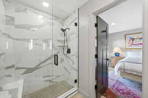 Bathroom featuring a marble finish shower, recessed lighting, and ensuite bathroom