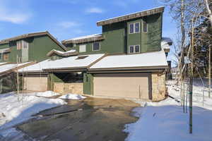 Contemporary home featuring an attached garage, driveway, and stone siding