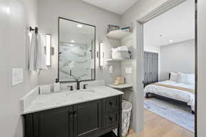 Bathroom with vanity, light wood-style floors, a marble finish shower, connected bathroom, and recessed lighting