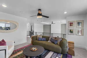 Carpeted living area with ceiling fan and recessed lighting