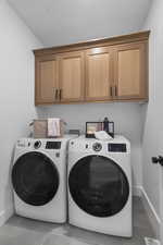 Washroom with cabinet space, tile patterned flooring, and washing machine and dryer