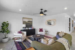 Living area featuring light colored carpet, ceiling fan, and recessed lighting