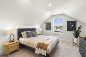 Bedroom featuring vaulted ceiling, light carpet, and electric panel