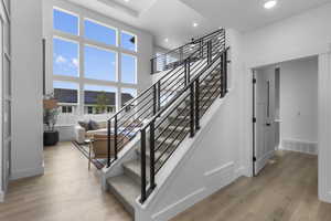 Stairway with wood finished floors, a high ceiling, and recessed lighting
