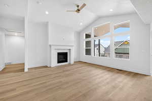 Unfurnished living room featuring high vaulted ceiling, light wood-style floors, a ceiling fan, a fireplace, and recessed lighting