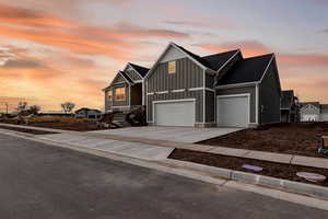 View of front of property featuring board and batten siding, concrete driveway, and a shingled roof