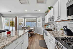 Kitchen featuring white cabinetry, appliances with stainless steel finishes, tasteful backsplash, light stone counters, and recessed lighting