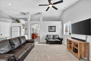 Living room with light carpet, vaulted ceiling, arched walkways, and ceiling fan