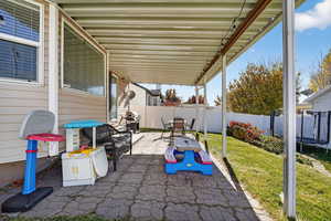Fenced backyard featuring a trampoline, a patio, a grill, and outdoor dining space