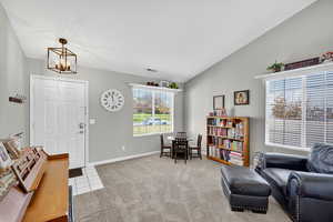 Living area with lofted ceiling, light carpet, light tile patterned floors, and a chandelier