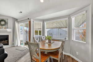 Dining area featuring a tile fireplace, wood finished floors, and vaulted ceiling