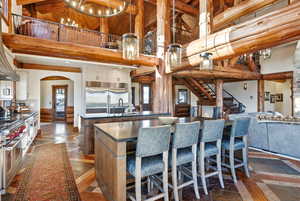 Kitchen featuring high vaulted ceiling, open floor plan, a kitchen bar, inlaid floor details, and high quality appliances