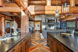 Kitchen with inlaid floor details, brown cabinets, a stone fireplace, open floor plan, and hanging light fixtures