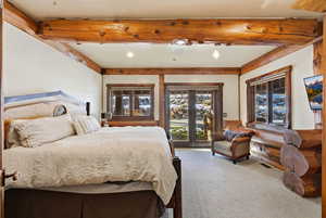 Bedroom featuring access to exterior, french doors, carpet floors, and beamed ceiling