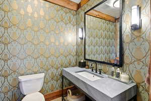 Half bathroom with vanity and wallpapered walls