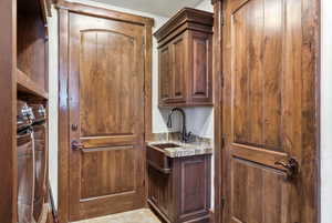 Bar featuring a sink and light stone counters