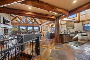 Kitchen featuring a high ceiling, beam ceiling, recessed lighting, inlaid floor details, and custom exhaust hood