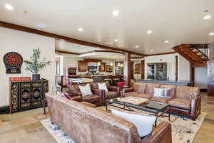 Living area with stone tile flooring, recessed lighting, and crown molding