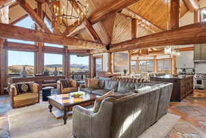 Living area featuring a chandelier, stone tile floors, high vaulted ceiling, a wood ceiling with exposed beams, and a mountain view
