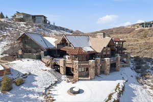 View of front of property with stone siding, a wooden deck, and a chimney
