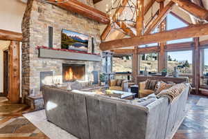 Living area featuring a fireplace, beam ceiling, high vaulted ceiling, a chandelier, and inlaid floor details