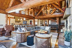 Living area featuring high vaulted ceiling, a wood ceiling with exposed beams, stairway, and a chandelier