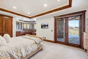 Bedroom featuring ornamental molding, access to outside, light colored carpet, a tray ceiling, and recessed lighting