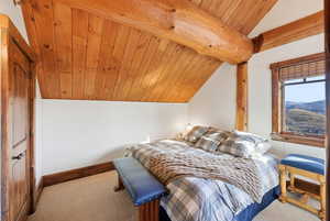 Carpeted bedroom featuring wooden ceiling and a mountain view