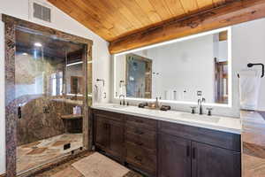 Full bath featuring a marble finish shower, double vanity, wooden ceiling, and lofted ceiling