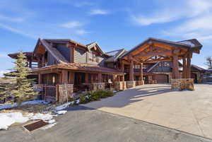 View of front of house featuring stone siding, driveway, a garage, and a tiled roof
