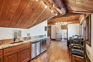 Kitchen with brown cabinets, wood ceiling, light wood-style flooring, stainless steel appliances, and light stone countertops