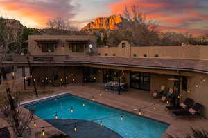 Back of house at dusk with a patio area, a tile roof, an outdoor pool, and stucco siding