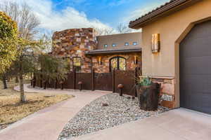 Doorway to property with a tile roof, stucco siding, stone siding, and a garage