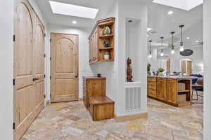 Entrance from Garage / Mudroom. Doorway with a skylight, recessed lighting, and stone tile floors