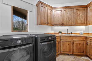 Laundry area featuring light stone finish flooring, cabinet space, and washing machine and clothes dryer