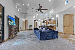 Living room featuring a ceiling fan, a high ceiling, stone tile flooring, a barn door, and recessed lighting