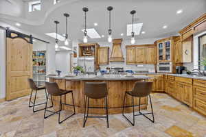 Kitchen with glass insert cabinets, an island with sink, a skylight, brown cabinets, and a kitchen breakfast bar