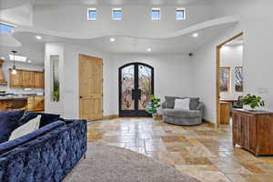 Foyer entrance with recessed lighting, stone tile floors, a high ceiling, and french doors