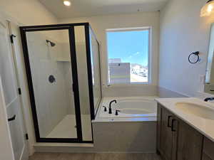 Bathroom featuring vanity, a stall shower, a bath, and recessed lighting
