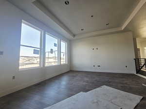 Empty room with a tray ceiling and dark wood finished floors