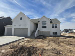 View of front of home featuring board and batten siding, a shingled roof, concrete driveway, and an attached garage