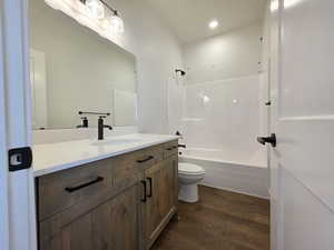 Full bathroom with vanity, dark wood finished floors, bathtub / shower combination, and recessed lighting