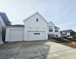 View of front of property featuring board and batten siding, driveway, and a garage