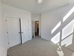 Unfurnished bedroom featuring a closet and light carpet