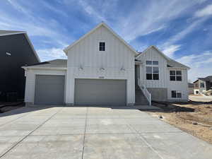 Modern inspired farmhouse with board and batten siding, driveway, an attached garage, and a shingled roof