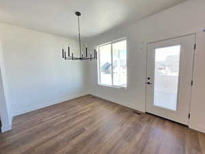 Unfurnished dining area featuring dark wood-type flooring and a chandelier