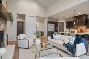 Living area with light wood-type flooring, a fireplace, recessed lighting, and a high ceiling