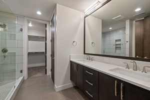 Full bathroom with a spacious closet, a shower stall, double vanity, light tile patterned flooring, and recessed lighting