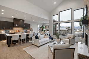 Living area with light wood-style floors, a fireplace with raised hearth, recessed lighting, high vaulted ceiling, and a mountain view
